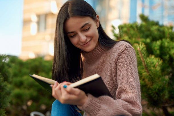 istock Smiling lady reading personal journal on the street 1239594935