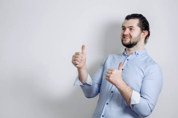 istock a man in a shirt on a gray background. It is shown that everything will be fine. 1239601520
