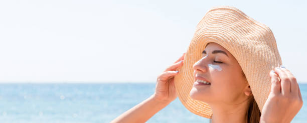 istock Smiling woman in hat is applying sunscreen on her face. Indian style 1239603193
