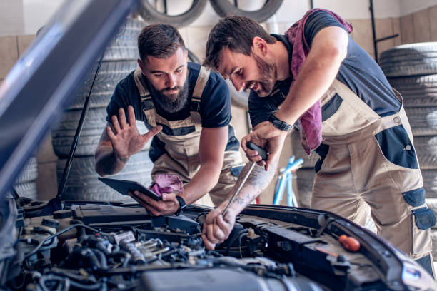 istock Two mechanics in uniform are working in auto service 1239624915
