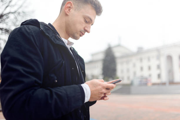istock Young man typing on phone on the street 1239637248