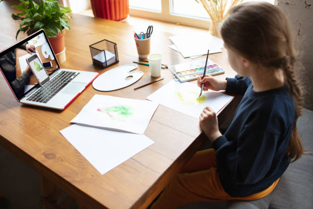 istock Girl drawing with paints and pencils at home, watching teacher's tutorial on laptop. Digitalization, remote education 1239645768