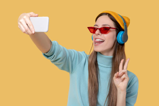 istock Girl photographing herself on a smartphone gesturing with her hand 1239665541