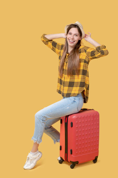 istock Beautiful long-haired girl in a hat sitting on a suitcase. 1239665587