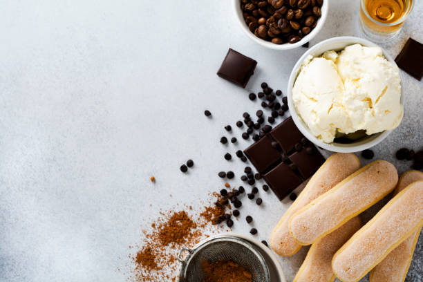 ingredientes para fazer tiramisu de sobremesa italiana, savoiardi, mascarpone, cacau em pó e chocolate em um fundo de concreto leve. vista superior com espaço de cópia. - biscotti italian culture cookie restaurant - fotografias e filmes do acervo