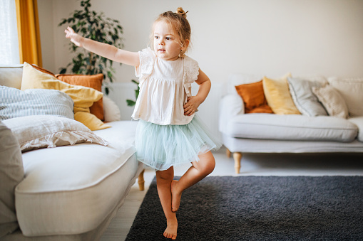 hot of an adorable little girl dressed up as a fairy showing off her ballet moves at home