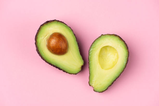 istock Avocado halves with core on pink background 1239687235