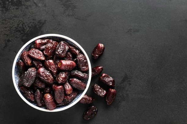 Dried dates in bowl on black background