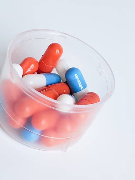 istock Capsules with medicine in a measuring Cup on a white background, close-up 1239694357