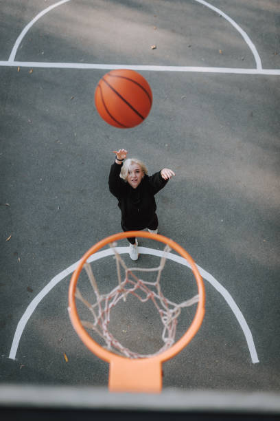 istock Happy pretty lady throwing ball into the basket 1239703803