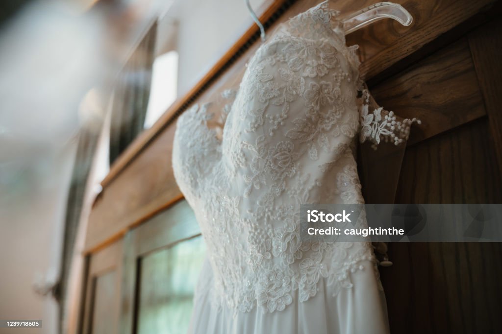 photo of a wedding dress hanged on a closet a wedding dress hanged on a closet Wedding Dress Stock Photo
