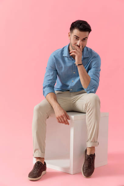 istock businessman sitting on cube and hiding smile behind fingers 1239731125
