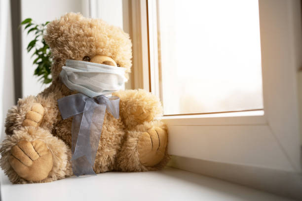 istock Coronavirus covid-19 and pollution protection concept. teddy bear doll wearing mask, sits on windowsill. 1239735510