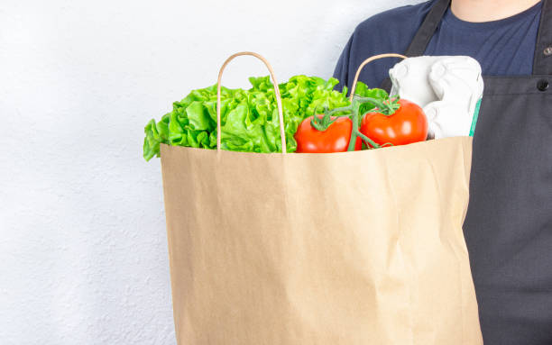 istock Man holding a paper bag with lettuce, tomato and eggs box 1239753631