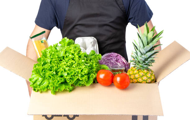 istock Man holding a carton box with lettuce, tomato and spaghetti, pineapple isolated on white 1239753662