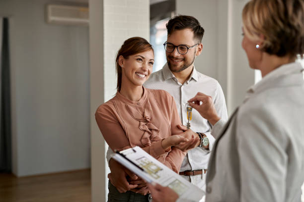 young happy couple receiving keys of their new home from real estate agent. - key imagens e fotografias de stock