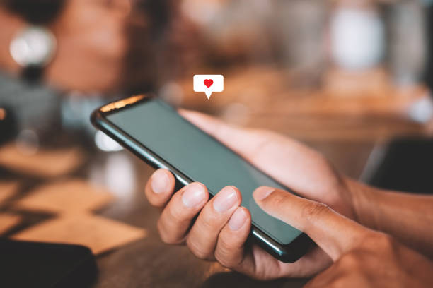 istock Man hand using smartphone with heart icon at coffee shop background. 1239759965