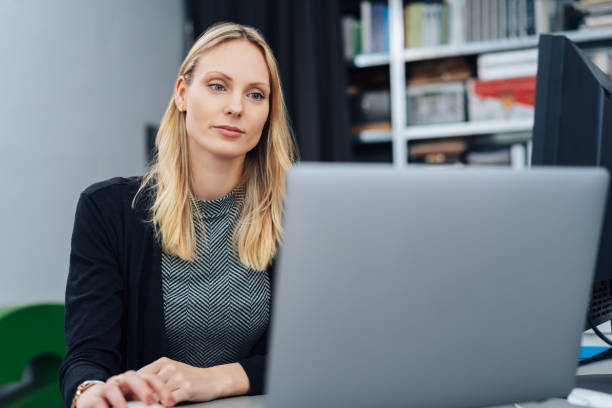 istock Young blond businesswoman working on a laptop 1239774665