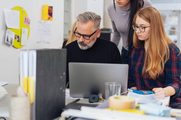 istock Young women gathered around mature man in office 1239776678