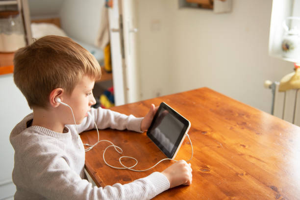 istock Smiling boy looking at digital tablet, wearing earbuds 1239811153
