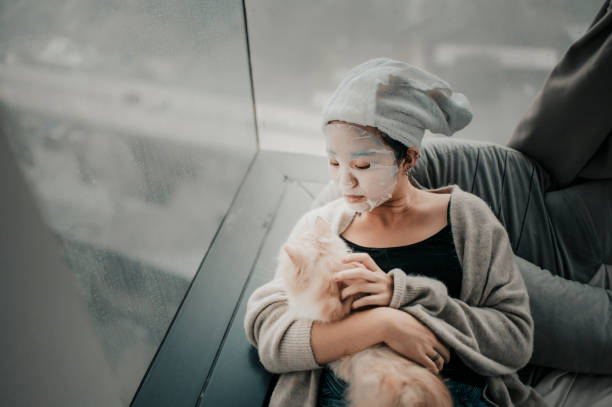 寝室で彼女の猫とフェイススパマスクをしているアジアの中国のティーンエイジャーの女の子 - health spa life purity satisfaction ストックフォトと画像