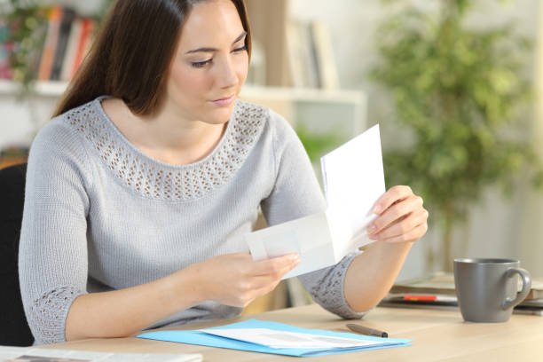 istock Woman opening envelope with letter at home 1239839609