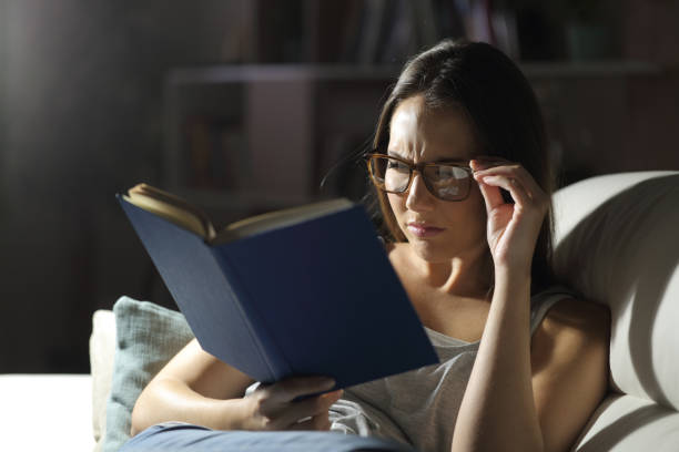 istock Woman with eyesight problem reads book at night 1239840129