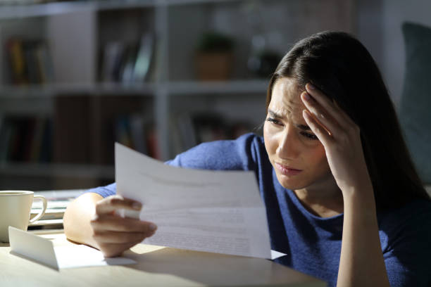 Worried girl reads bad news on letter at night at home Worried girl reads bad news on letter at night at home eviction photos stock pictures, royalty-free photos & images