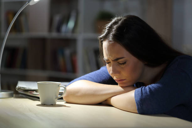 mulher triste reclamando deitado na mesa à noite em casa - teenager dark pensive emotional stress - fotografias e filmes do acervo