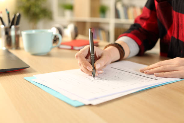 istock Student hands filling out application form at home 1239844481