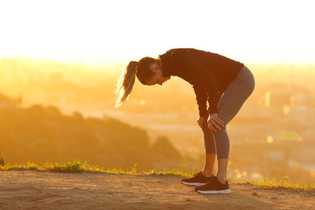Tired runner resting after exercise in city outskirts Tired runner resting after exercise in city outskirts exhaustion photos stock pictures, royalty-free photos & images