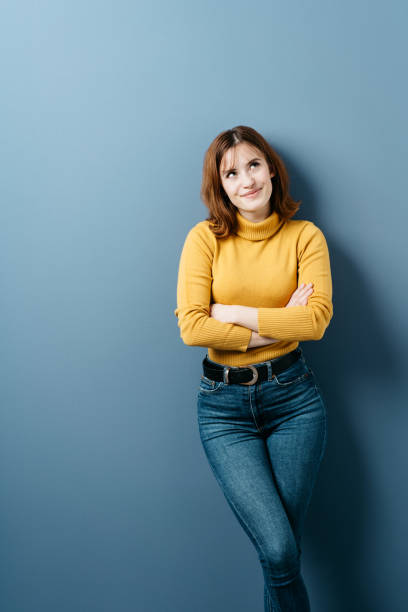 istock Trendy young woman in jeans standing thinking 1239846056