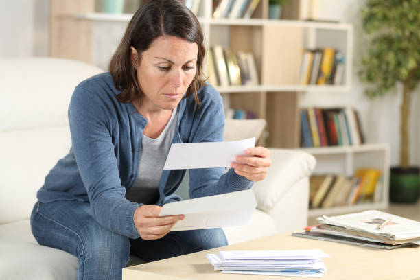 serious adult woman looking receipts at home - opening mail letter envelope imagens e fotografias de stock