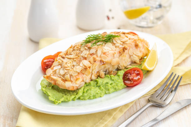 Salmon fillet fried in almond petals. Garnished with cauliflower and green peas puree. stock photo