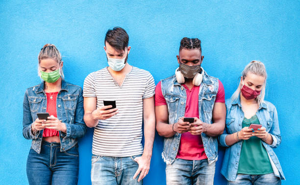 istock Multiracial friends with face masks using tracking app with mobile smart phones - Young millenial people sharing content on social media networks - New normal lifestyle concept - Bright vivid filter 1239854295
