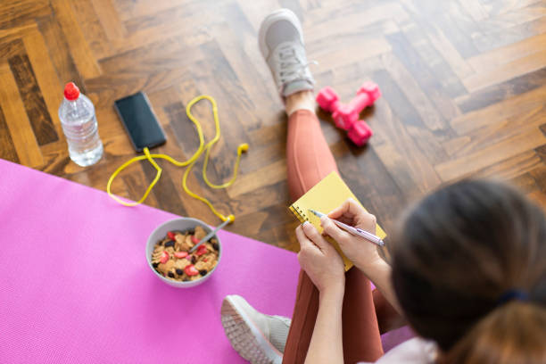 Young sporty woman writing workout plan in notebook after a workout