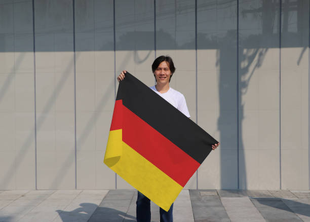 istock The man is holding Germany flag in his hands on grey background. 1239907212