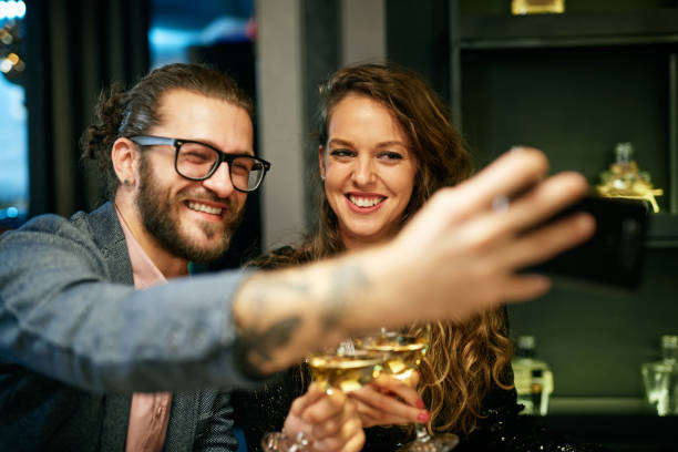 istock Smiling couple sitting in restaurant toasting with white wine and taking selfie. 1239919010