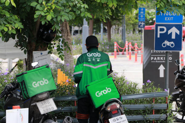 Grab bike in green corporate color of jacket and the box to put food. He is prepared to go to deliver food. stock photo