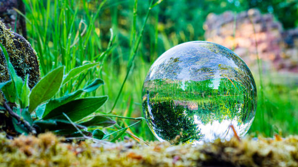A lensball reflects a lush green landscape with an old castle ruin. stock photo