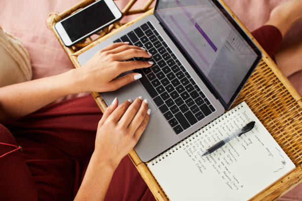 istock Woman sitting on her bed working on a laptop 1239937498