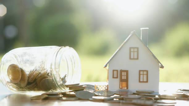 istock Coins on glass vase with house model. 1239938566