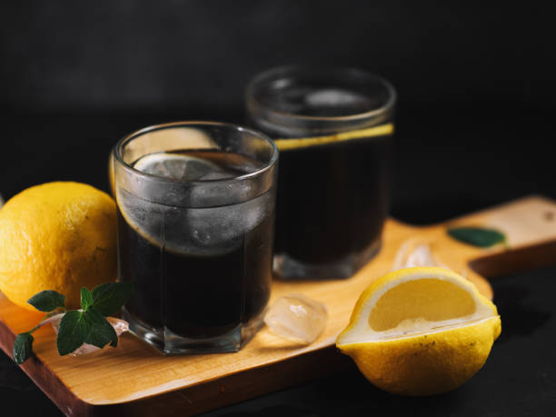 refreshing summer detox lemonade with charcoal and mint on a black table.
