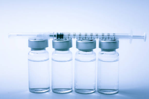 istock Vaccines, botulinum toxin and insulin ampules concept theme with glass vials with clear liquid next to a syringe and a hypodermic needle isolated on blue background 1239955433