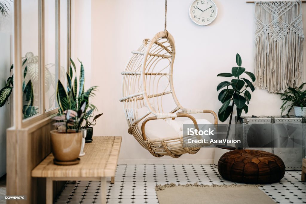 Cozy hanging chair in the loft living room with stylish and bohemia design. Well designed and decorated with an assortment of interesting plants Boho Stock Photo