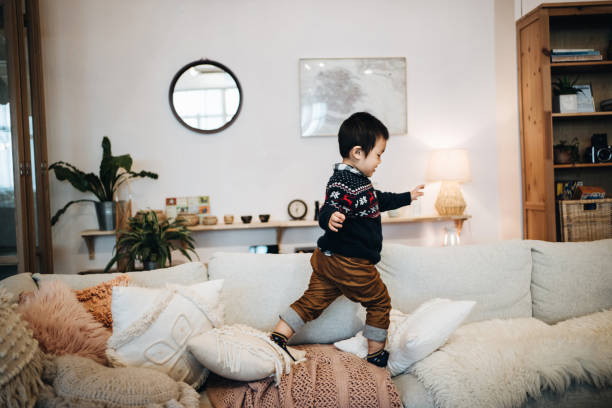 自宅でソファで走ったり飛び降りったりする小さなアジアの少年 - domestic life jumping child sofa ストックフォトと画像