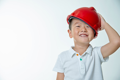 Little boy engineer with protective helmet against white background.