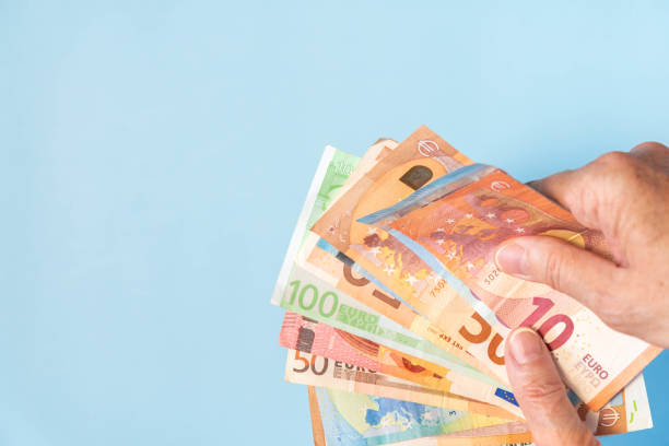 istock Person hands holding euro notes on blue background with copy space 1239992477
