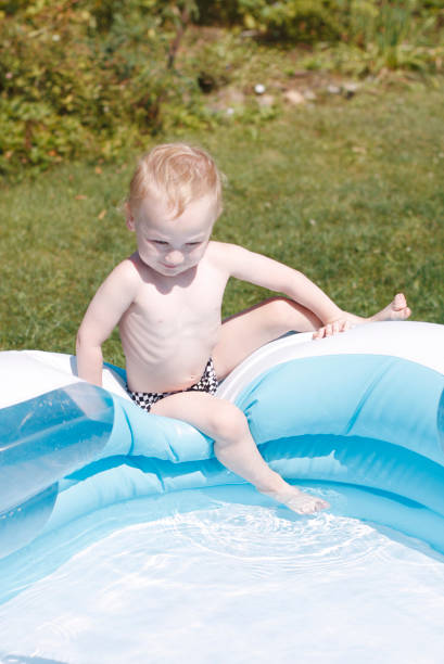 istock Cute little boy sitting in swimming pool 1240005134
