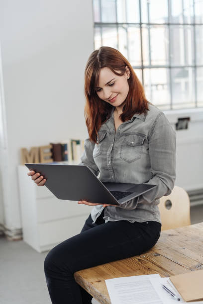 istock Attractive young businesswoman perched on a table 1240017923